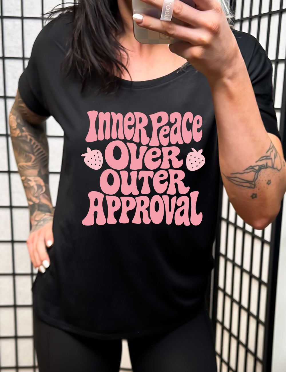 black slouchy tee with the words "inner peace over outer approval" on it, with two small strawberry graphics on either side of the word "over"