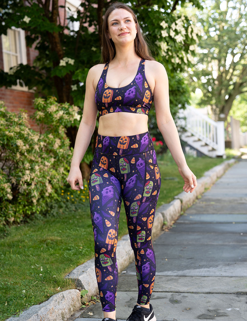 model wearing the zombie, jack o lantern, and ghost ice cream's full length leggings and sports bra taking a walk outside