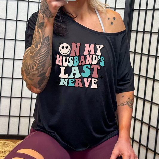 model wearing a black slouchy tee with the saying "on my husband's last nerve" on it