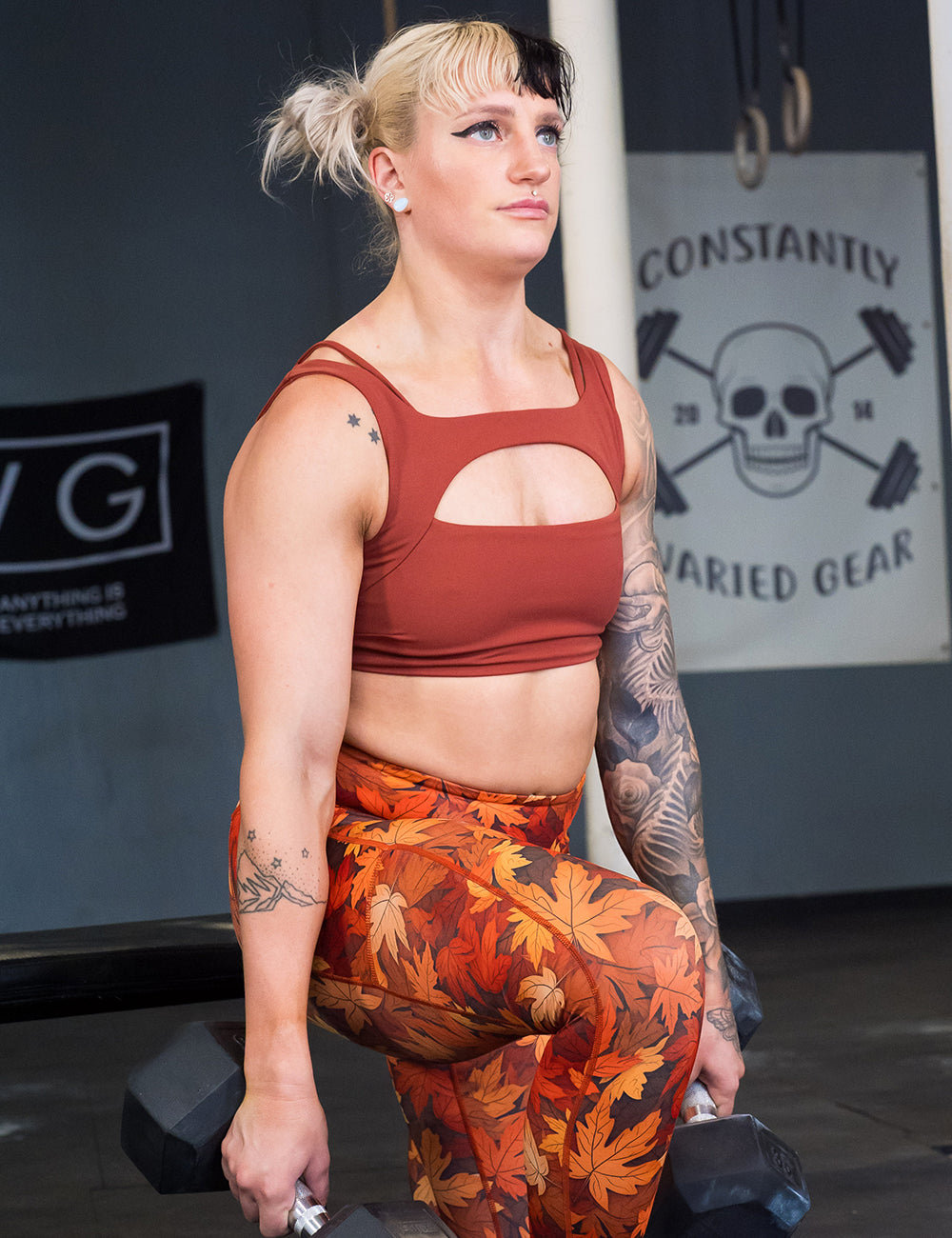 model wearing the solid auburn bra and orange leaves leggings working out in the gym