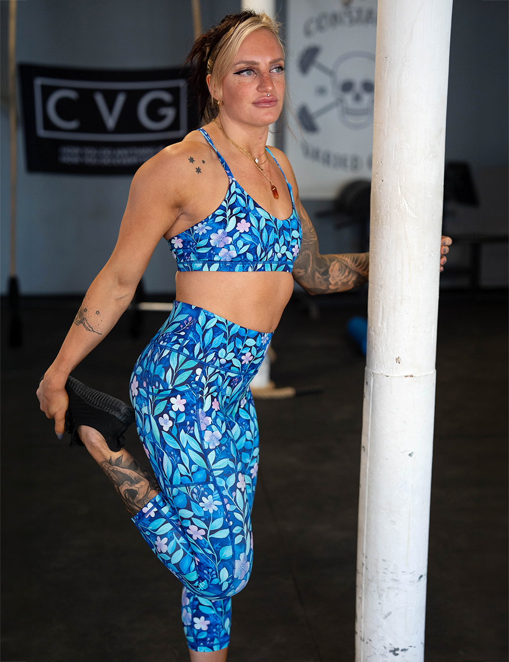 model wearing the blue flowers and vines capri leggings stretching in the gym