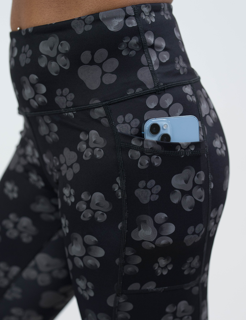 close up of the grey paw print against a black background leggings pocket with a phone inside