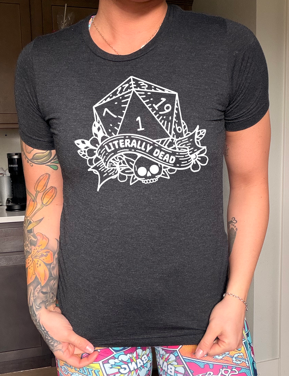 black unisex tee with the graphic of a dungeons and dragons die (with the numbers 17, 3, 7, 1, 19, and 6 showing) above a skull among flowers, and a small banner reading "literally dead" 
