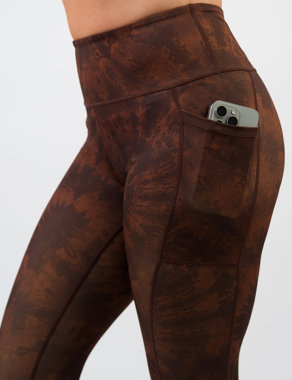 front of the brown tie dye leggings with a close up of a phone in its pocket