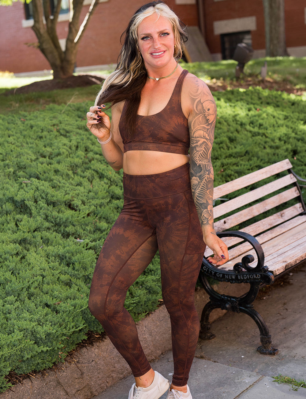 model wearing the full length brown tie dye leggings and sports bra posing in a park