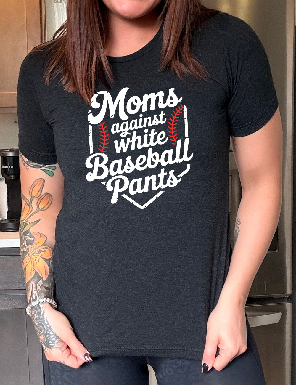 black unisex tee with the words "moms against white baseball pants" on it, bordered by the baseball diamond, with baseball stitching on both sides of the words
