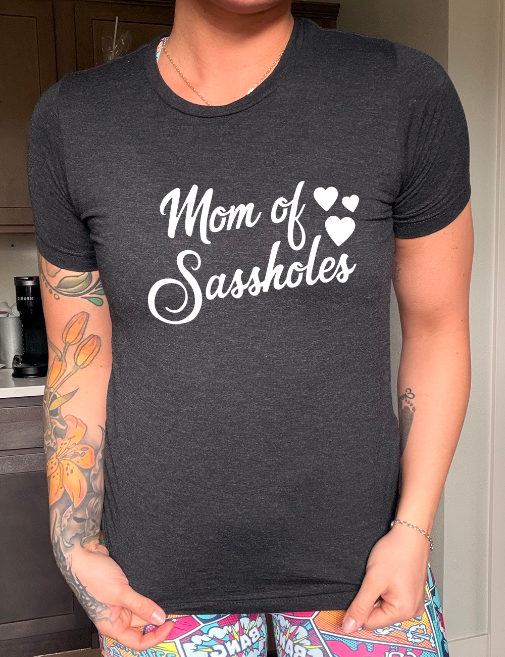 black unisex tee with the words "mom of sassholes" on it, with three little hearts next to the words