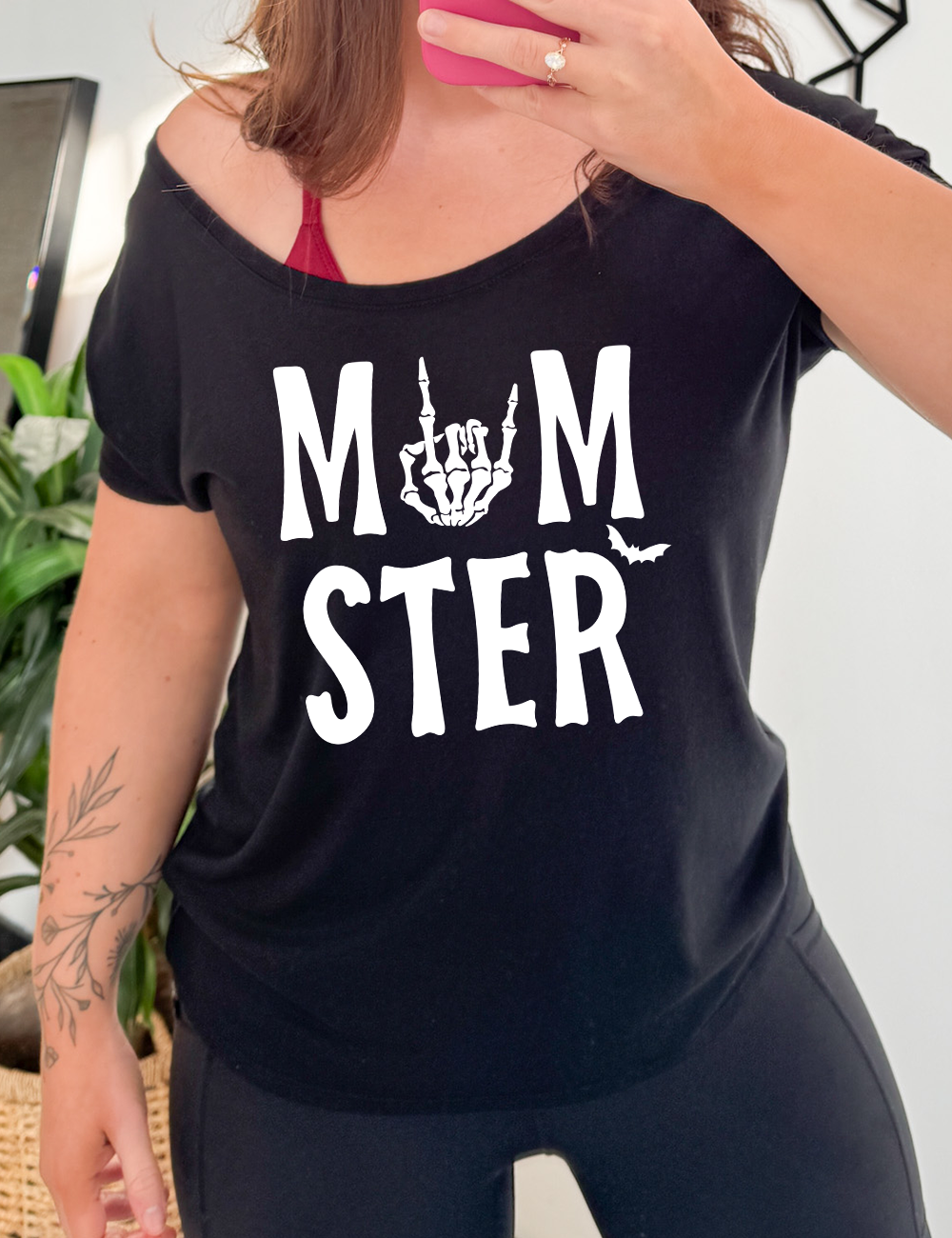 black slouchy tee with the word "momster" on it, with the "o" of the word being the graphic of a skeletal rocker hand, and one little bat after the word