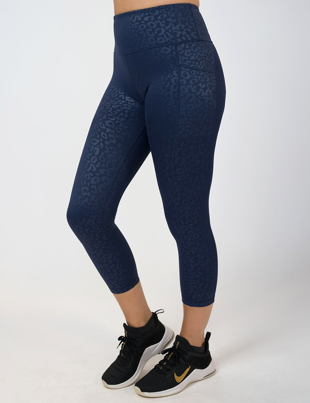 model wearing the capri dark blue leopard print leggings against a white background