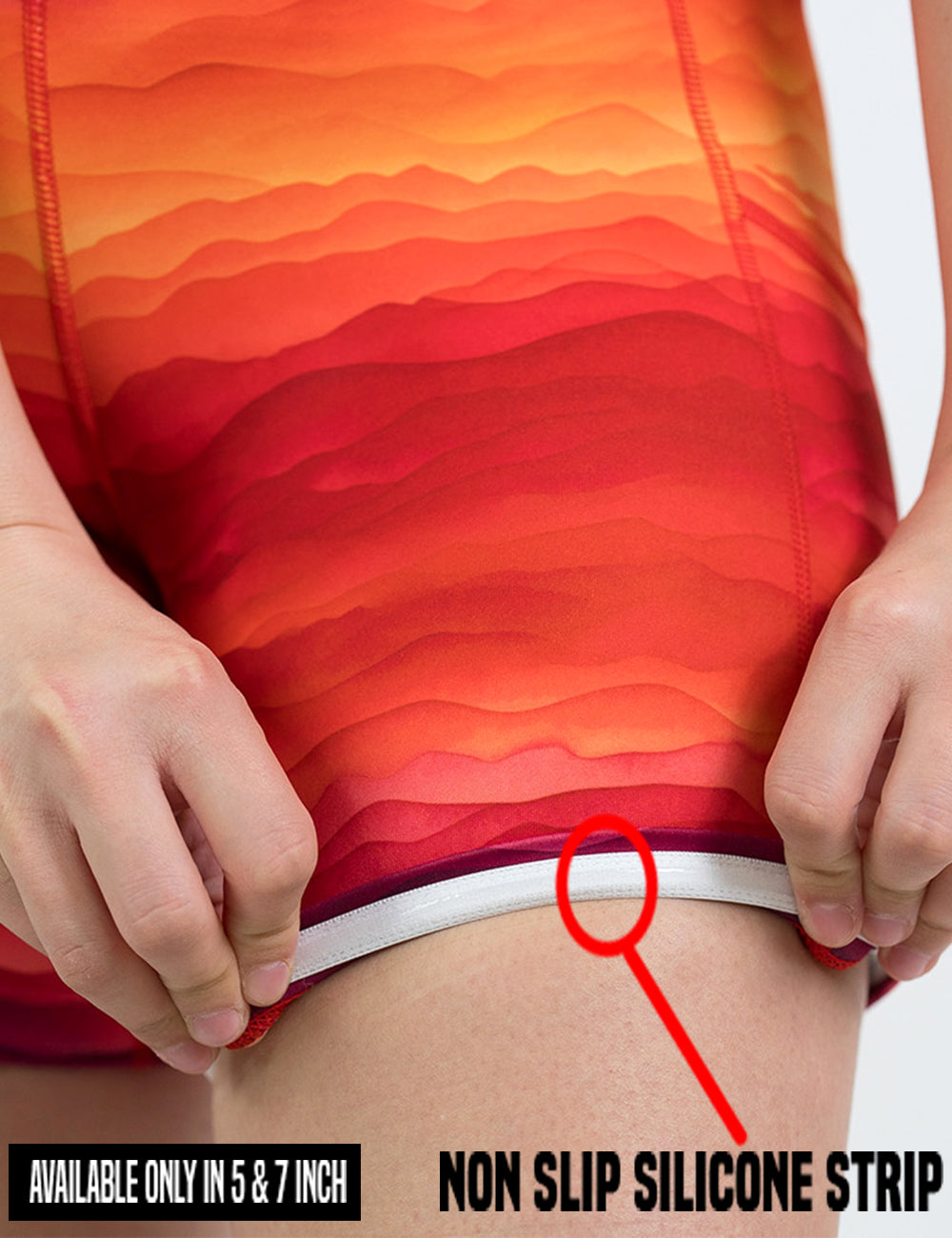 close up of the red, yellow, and orange sunset stripes pattern shorts being rolled up to show the non slip silcone strip found in the lining of the 5 and 7 inch shorts