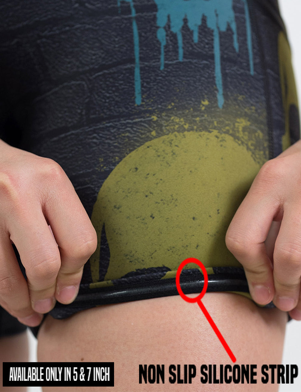 close up of the black brick pattern with blue, red, and yellow skull spray paint patterns shorts being rolled up to show the non slip silicone strip pattern found in the lining of the 5 and 7 inch shorts