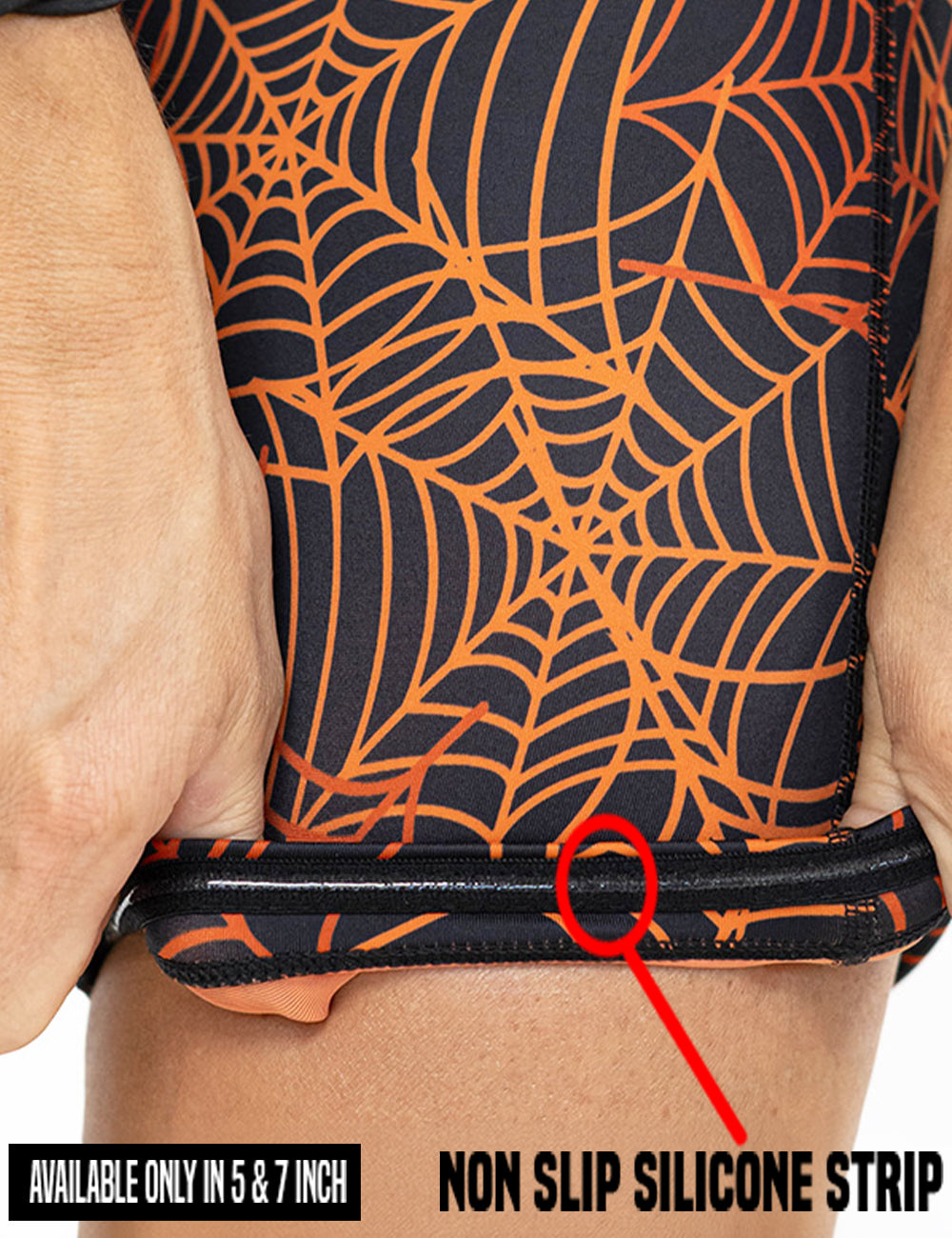 close up of the orange spider webs against a black background shorts being rolled up to show the non slip silicone strip found in the 5 and 7 inch shorts