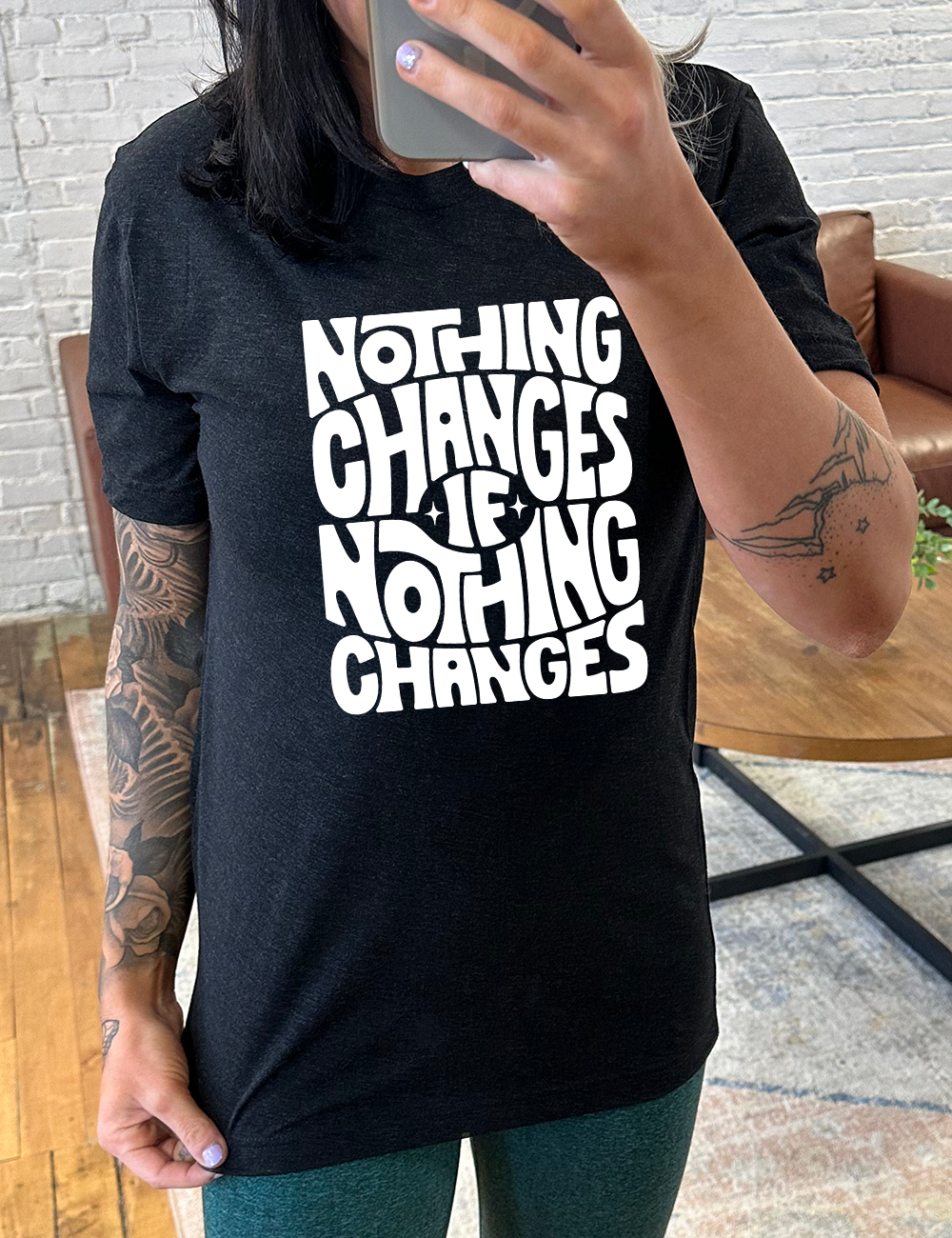 black unisex tee with the words "nothing changes if nothing changes" on it, with two tiny stars on either side of the word "if"