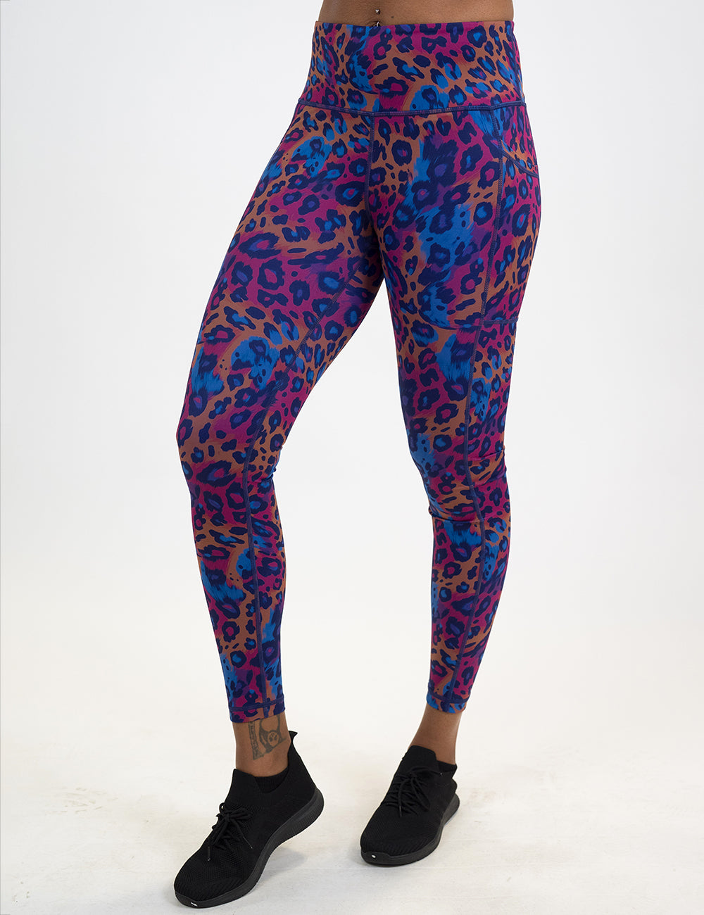 model wearing the full length red, yellow, and blue cheetah print leggings against a white background