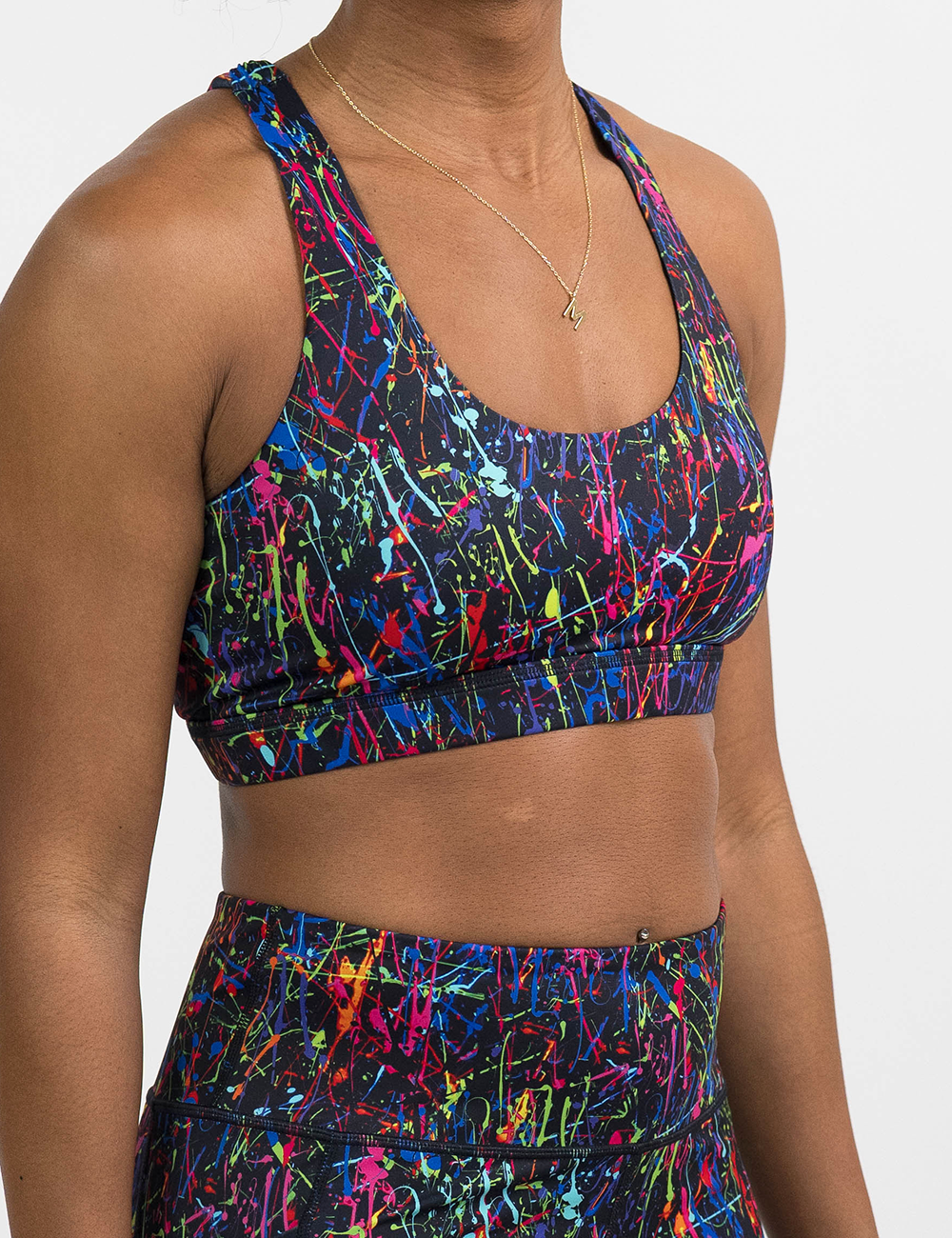 front of the rainbow paint splatter against a black background butterfly back bra