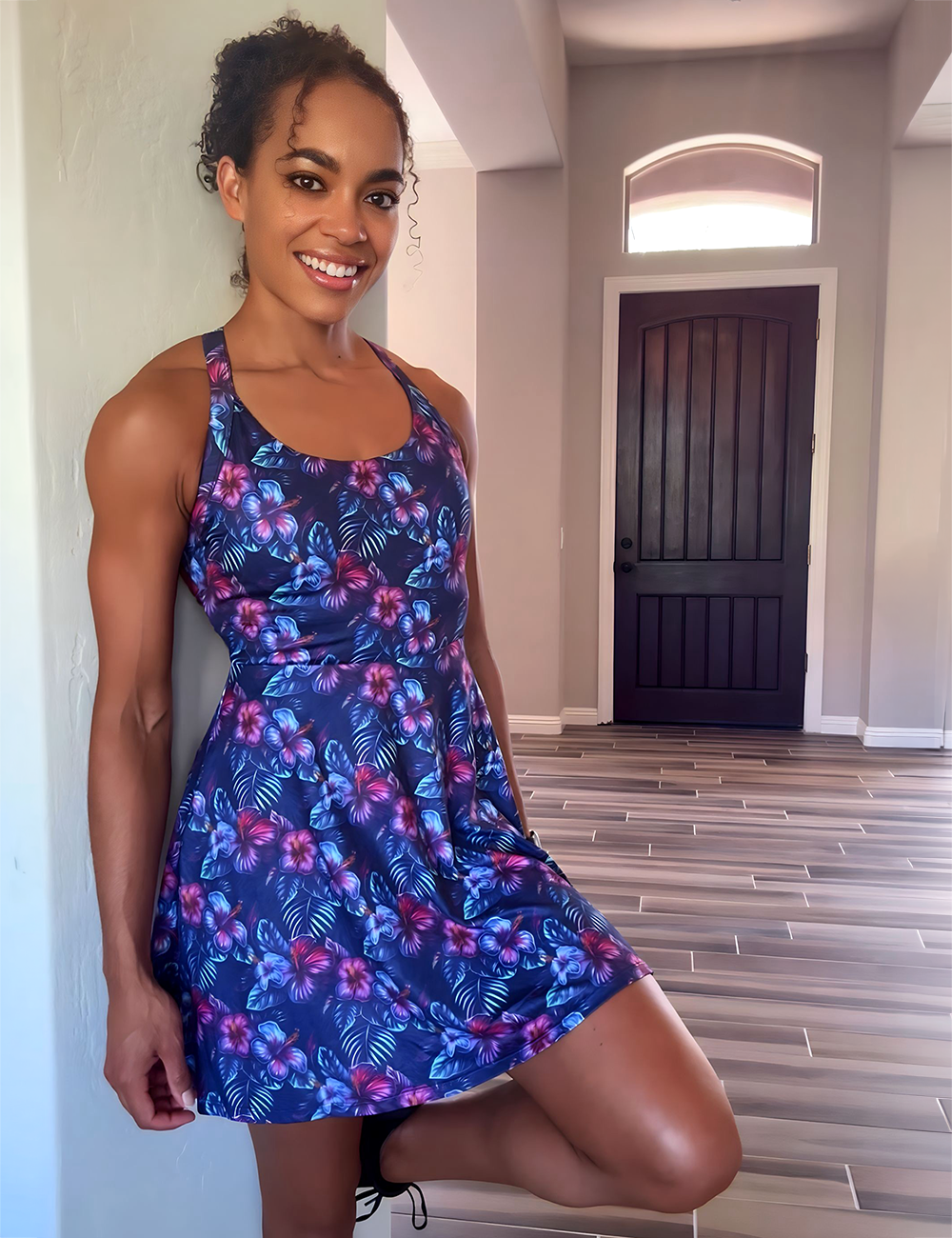 model wearing the blue, purple, and red tropical flower dress in a entry way in front of a door