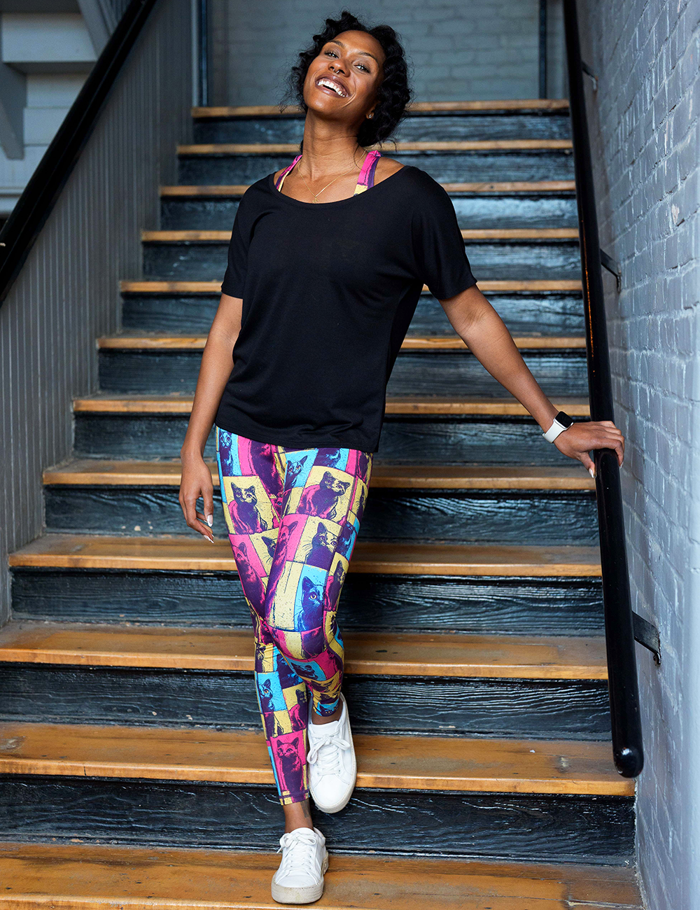 model wearing the red, yellow, and blue cat leggings in a stairwell
