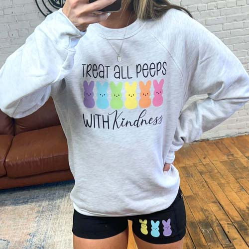 Model wearing a ash grey crew neck with the design "treat all peeps with kindness" on it. 6 colorful peep images are under the text