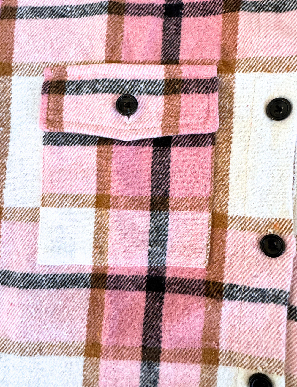 close up of the pink, brown, black, and white plaid jacket