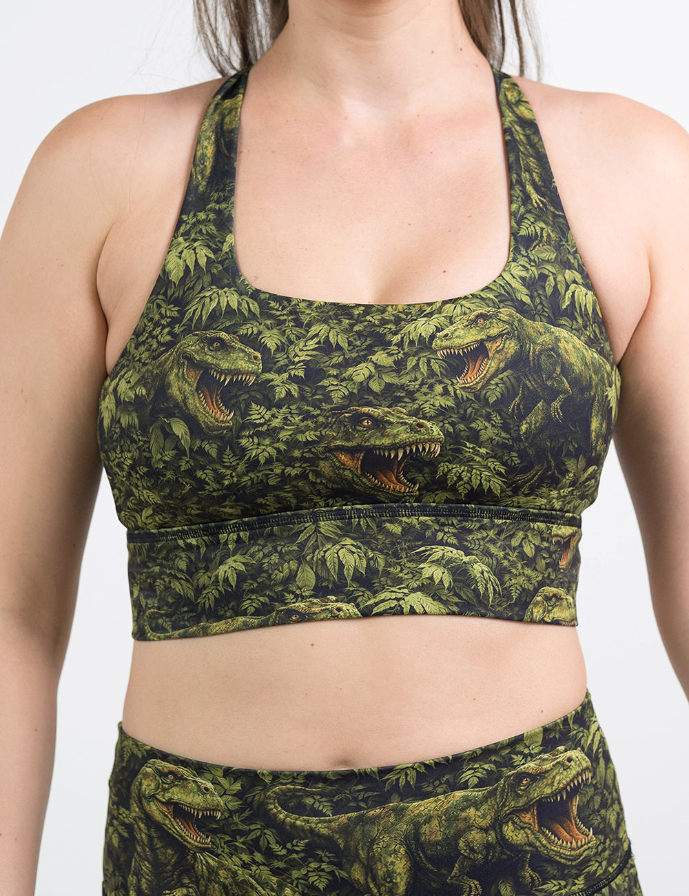 front of the t-rex in a rainforest longline bra against a white background