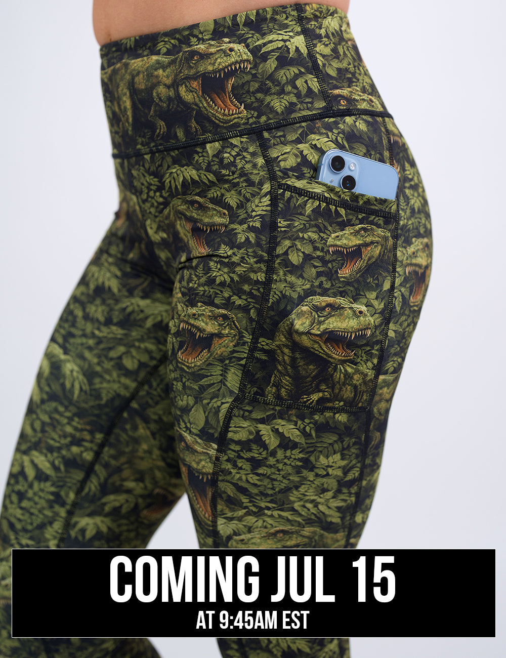 close up of the green t-rex in a forest leggings holding a phone in its pocket against a white background, coming july 15th