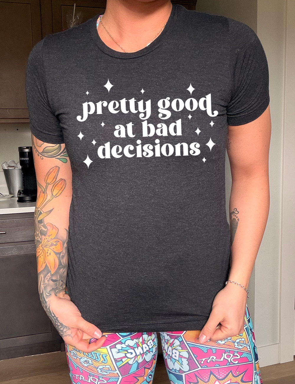 black unisex tee with the words "pretty good at making bad decisions" on it, with a few little stars scattered around the words