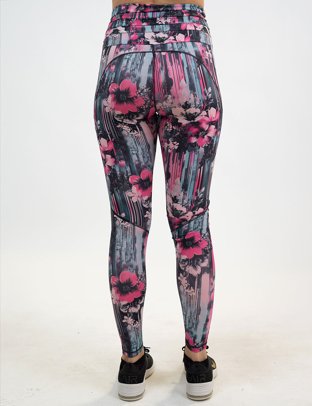 back of the pink flowers against a bold teal and pink striped background pattern leggings against a white background