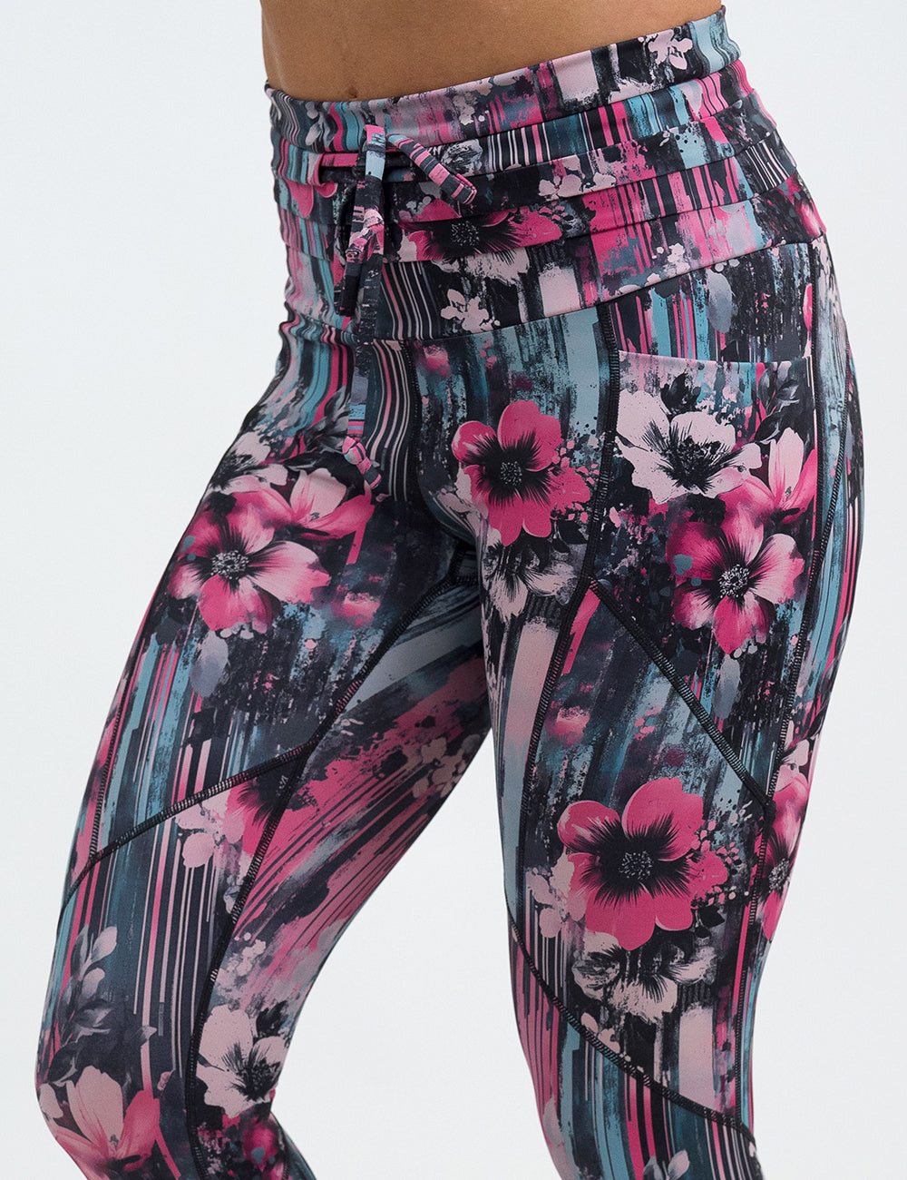 front of the pink flowers against a bold teal and pink striped background pattern leggings against a white background
