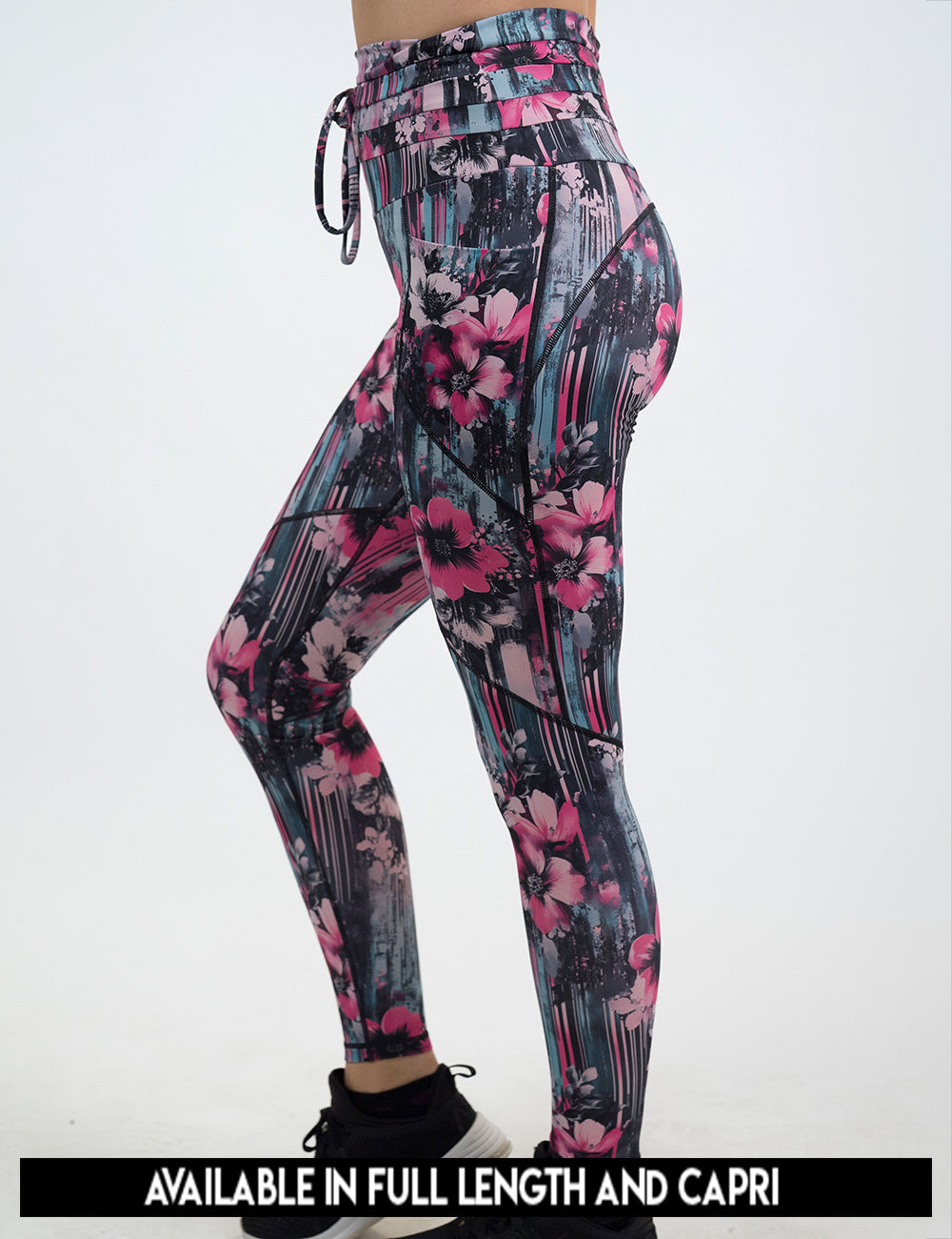 available lengths for the pink flowers against a bold teal and pink striped background pattern leggings, lengths include full length and capri
