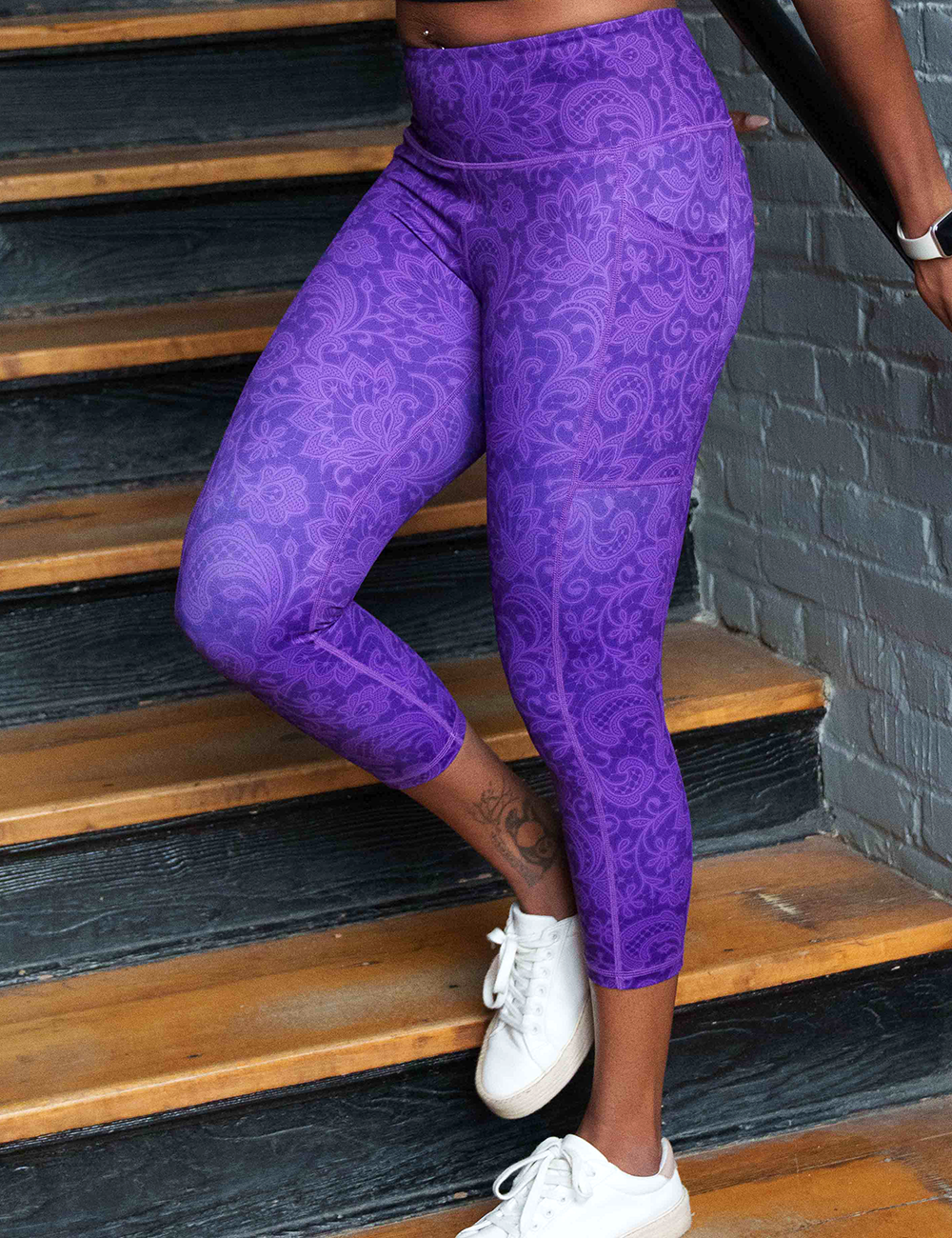 model wearing the purple flower artwork capri leggings walking down the stairs