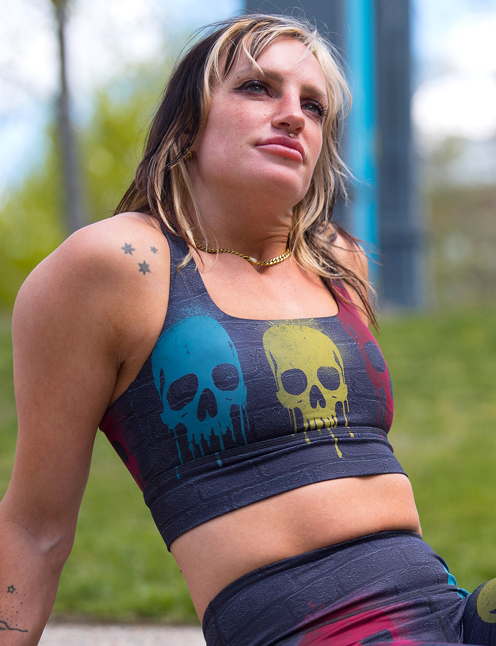 model wearing the black brick pattern longline bra with spray painted yellow, blue and red skulls all over