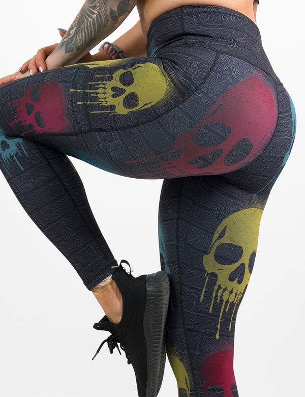 back of the black brick full length leggings with spray painted red, yellow, and blue skulls all over against a white background