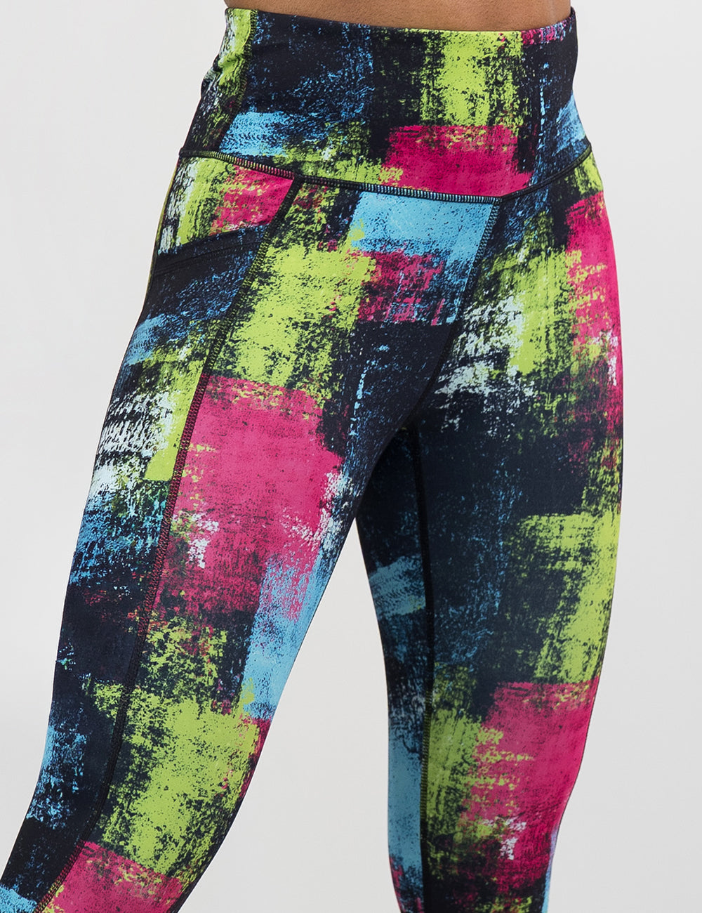 front of the green, pink, and blue grunge pattern leggings against a white background