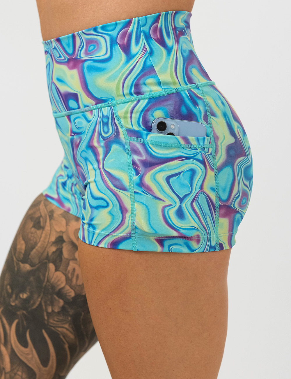 close up of the 2.5 inch blue, green, and lavender liquid pattern shorts with a phone in its pocket