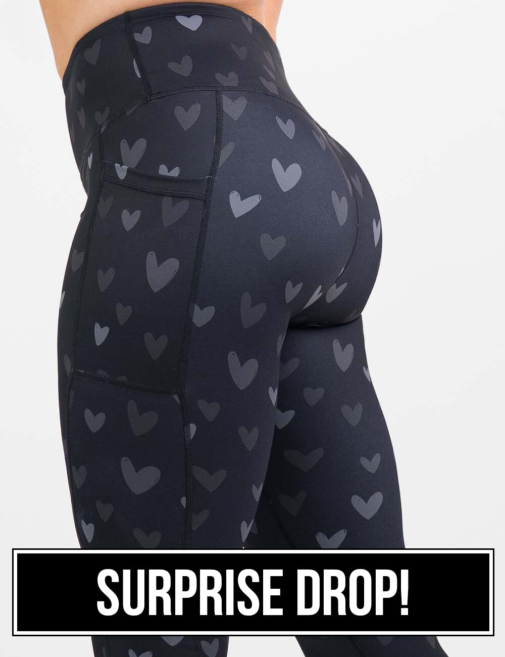 side view of the black leggings with light and dark grey hearts against a white background, surprise drop
