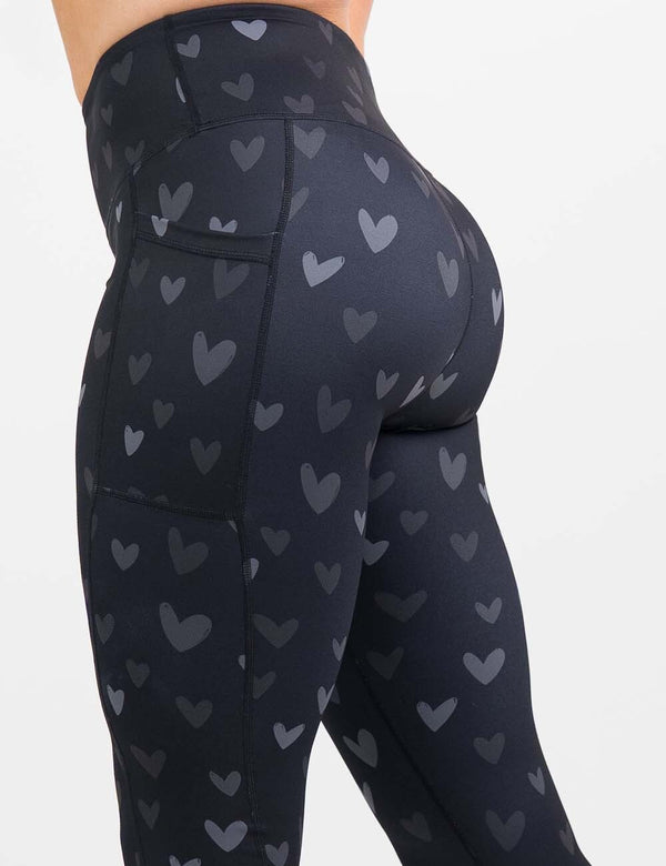 side view of the black leggings with light and dark grey hearts against a white background