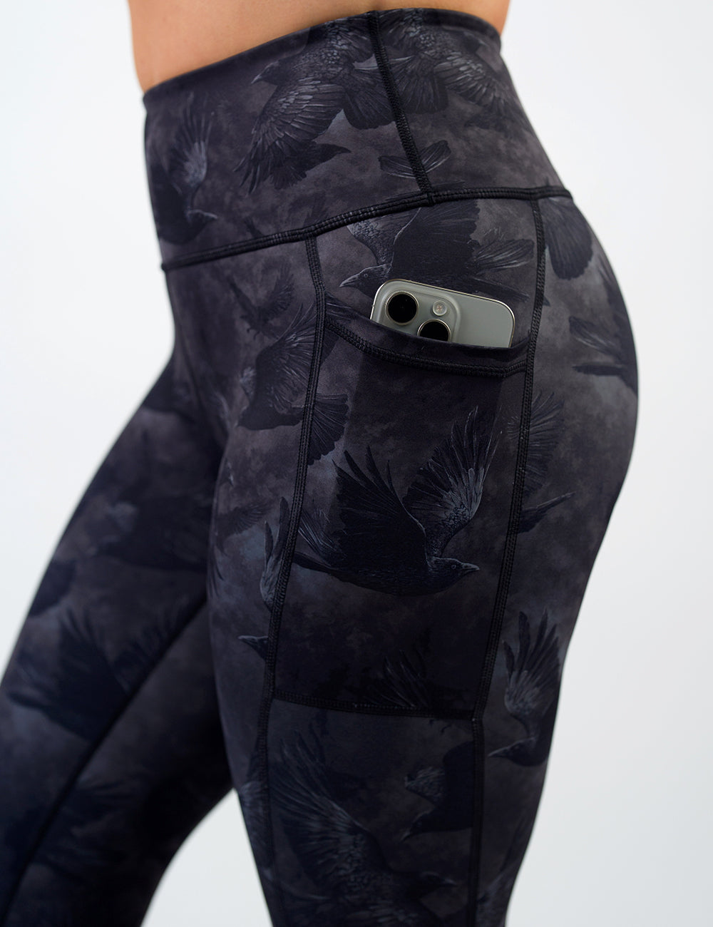 close up of the dark ravens against a smokey grey and black background leggings with a phone in its pocket