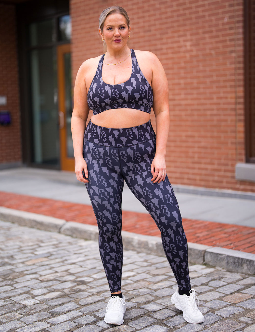 model wearing the full length black leggings with a grey thunderbolts pattern