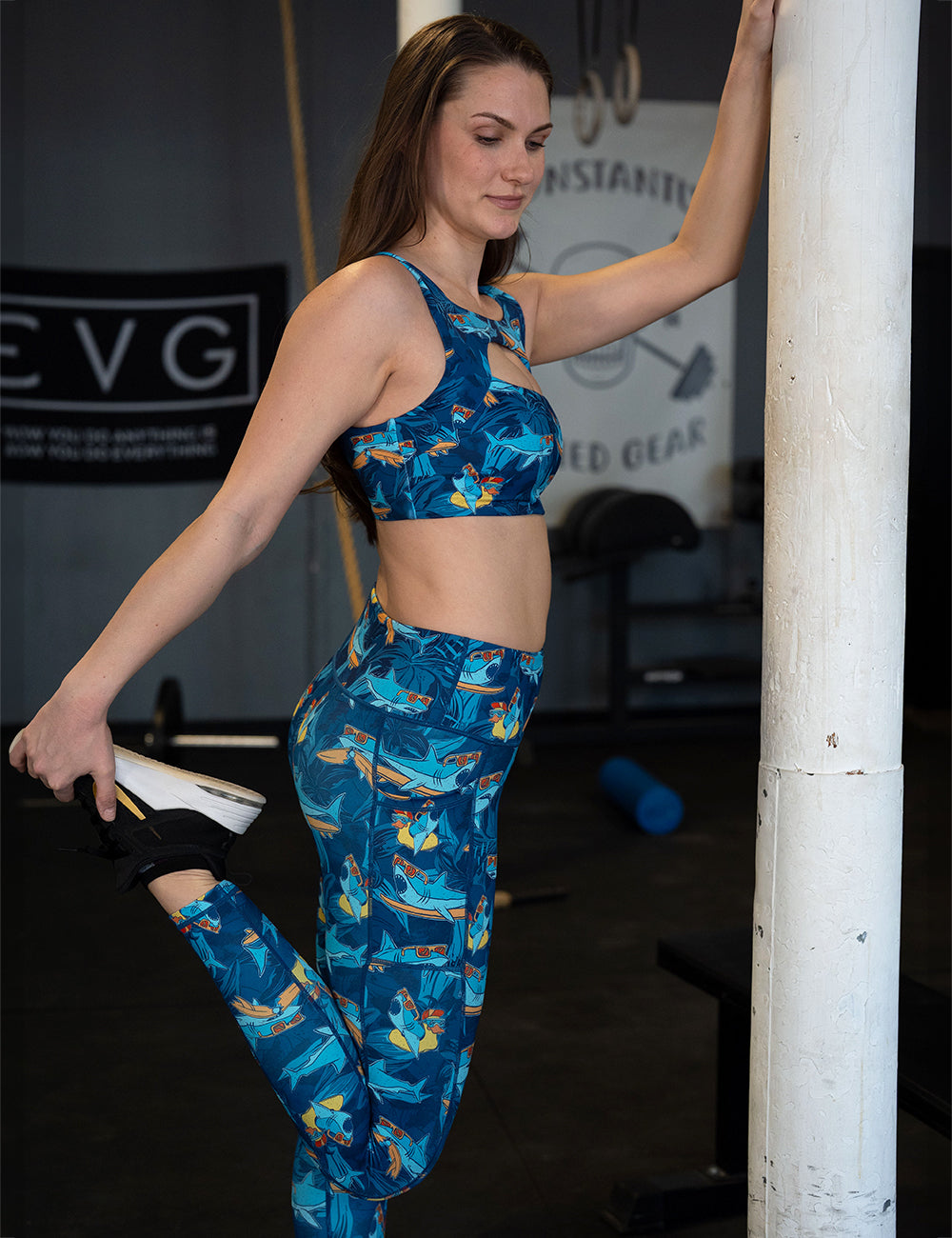 model wearing the full length cartoon sharks surfboarding with sunglasses leggings in the gym stretching