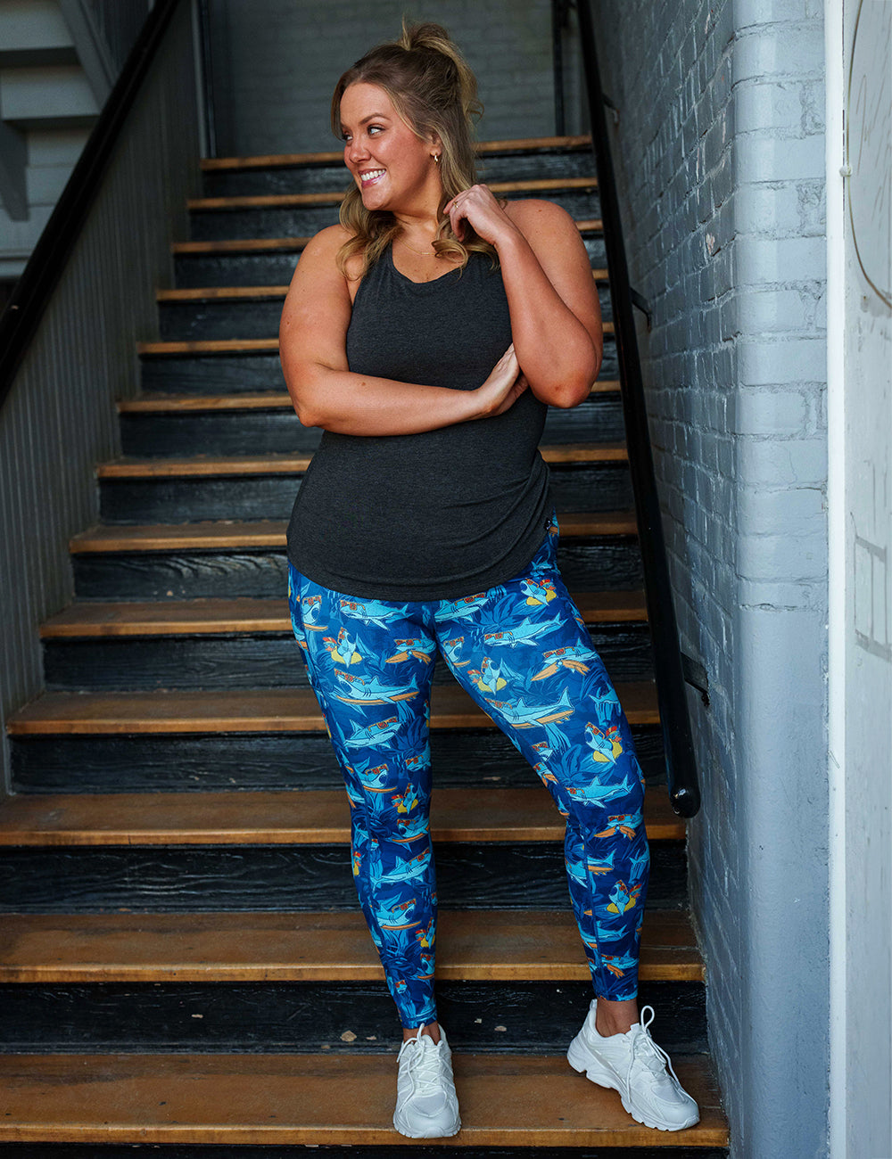 model wearing the cartoon sharks surfboarding with sunglasses capri leggings in a stairwell