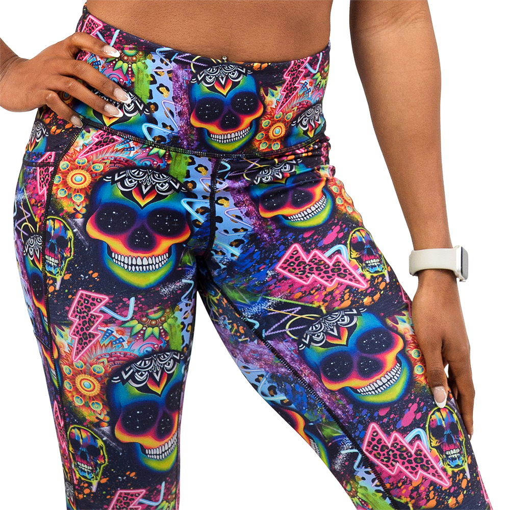 close up of the brightly colored psychedelic skulls pattern against a busy background full of designs leggings against a white background