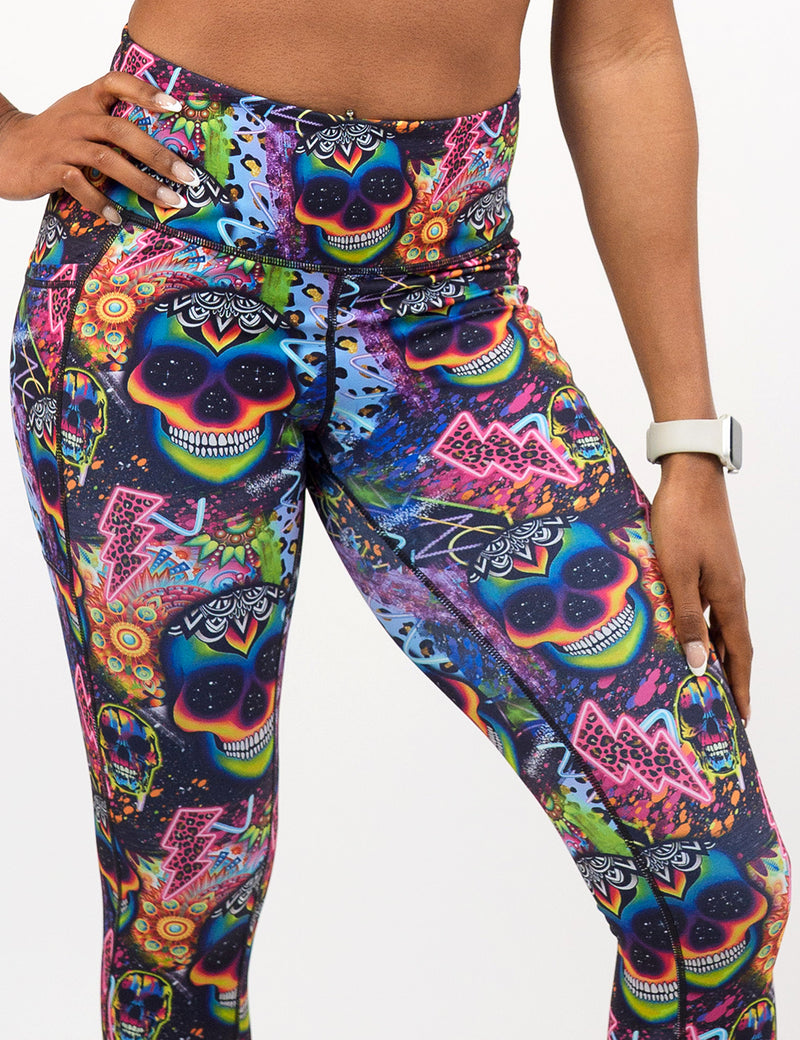 close up of the brightly colored psychedelic skulls pattern against a busy background full of designs leggings against a white background
