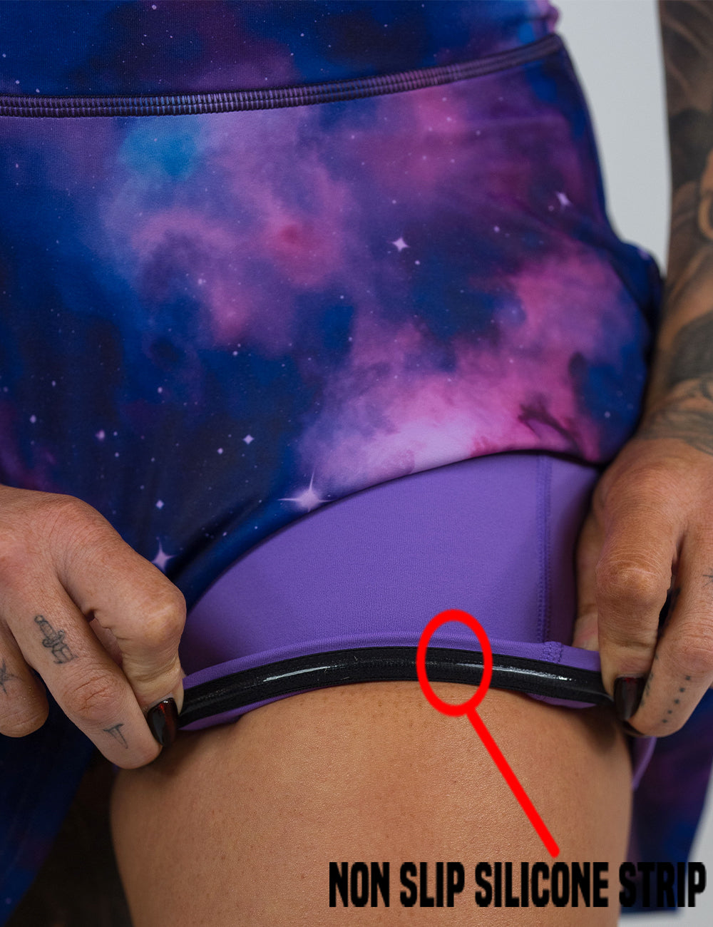 close up of the blue and purple cosmos pattern skirt being rolled up to show the non slip silicone strip found in the lining of the under shorts