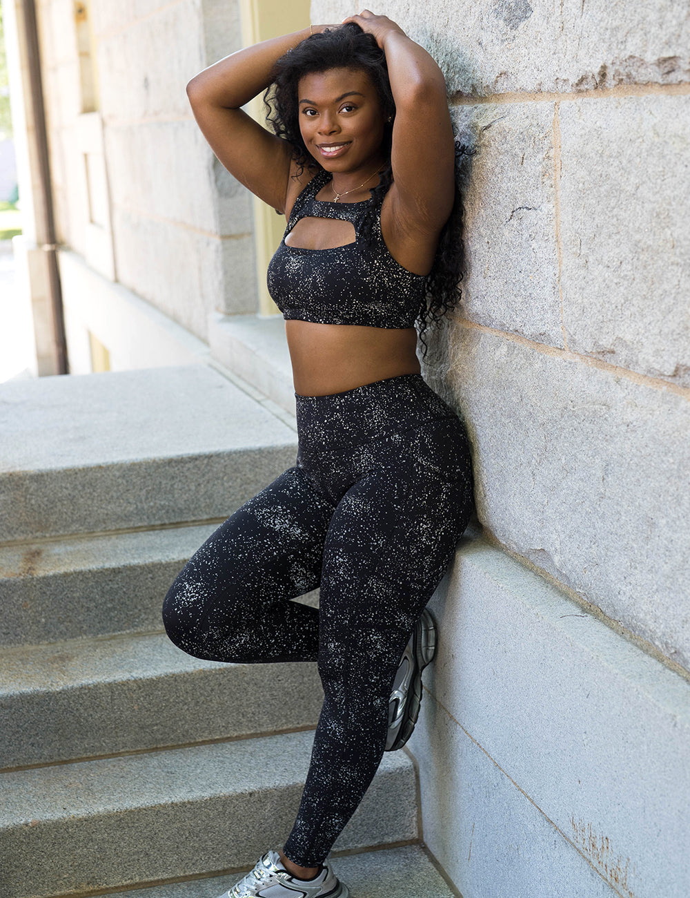 model wearing the full length black leggings with reflective spots leggings and sports bra