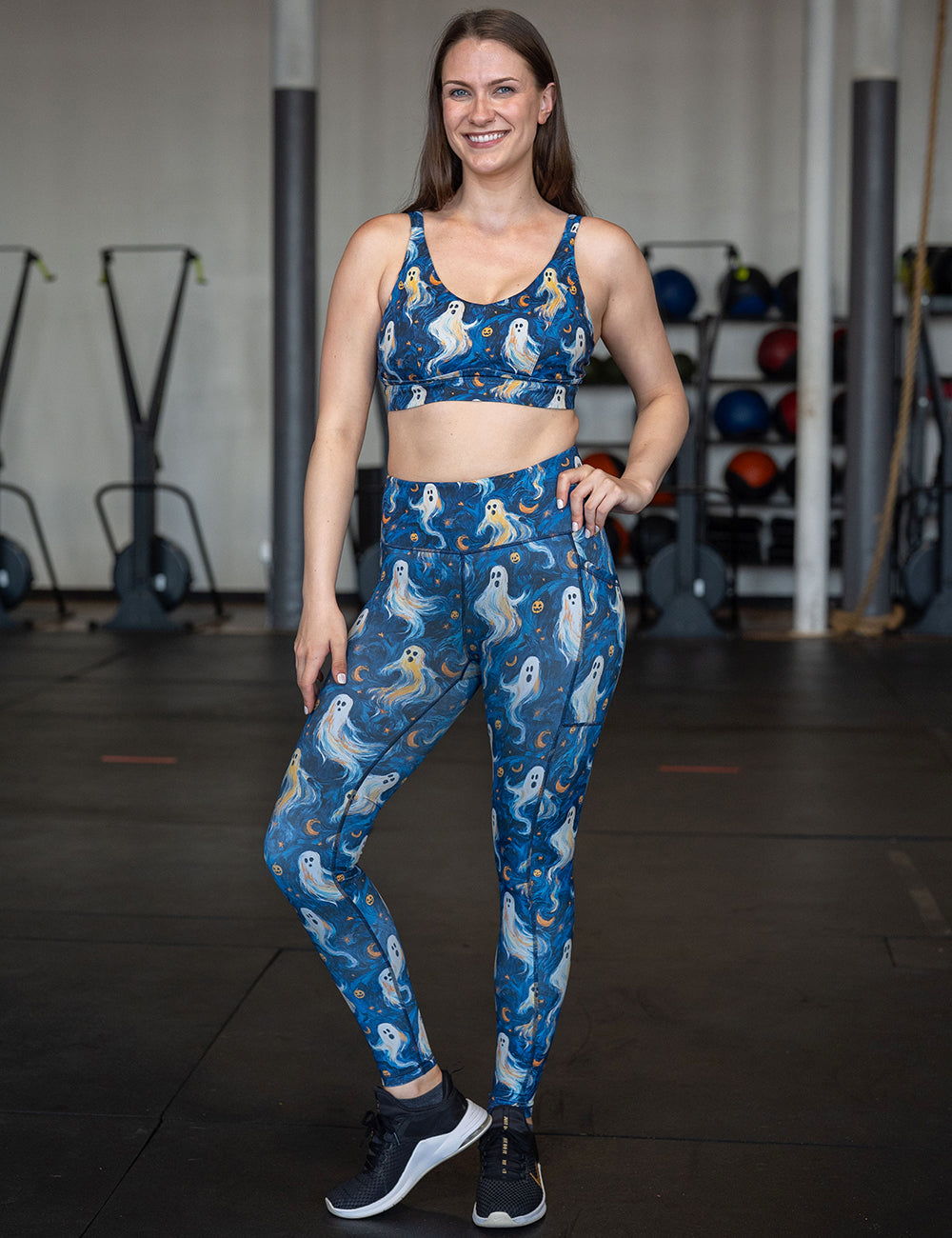 model wearing the starry night ghosts against a blue background pattern full length leggings and bra in the gym