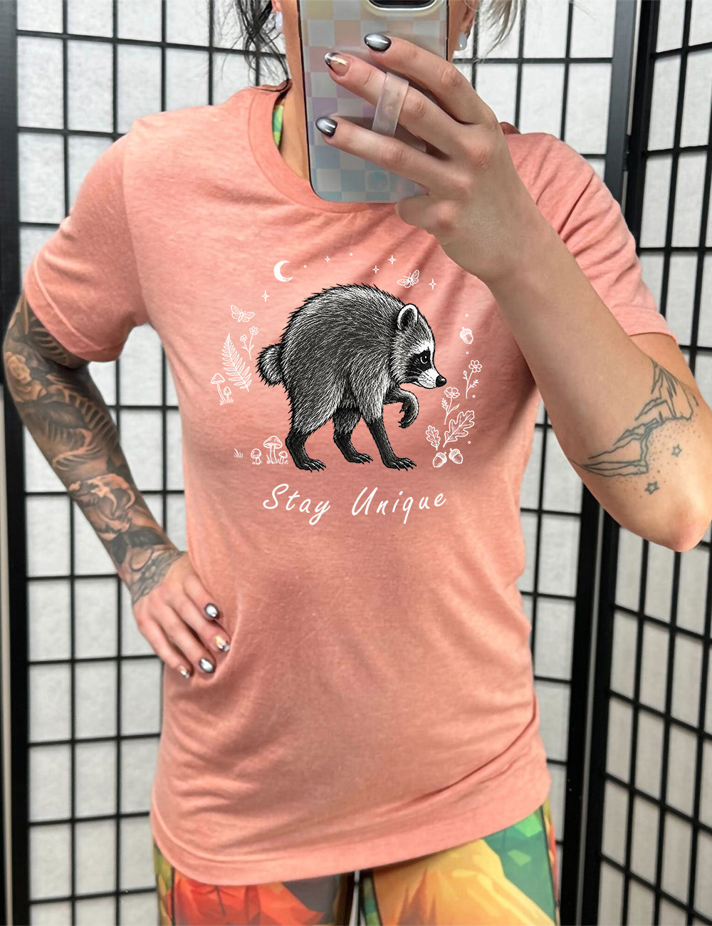 front of the orange sunset "stay unique" raccoon unisex tee 