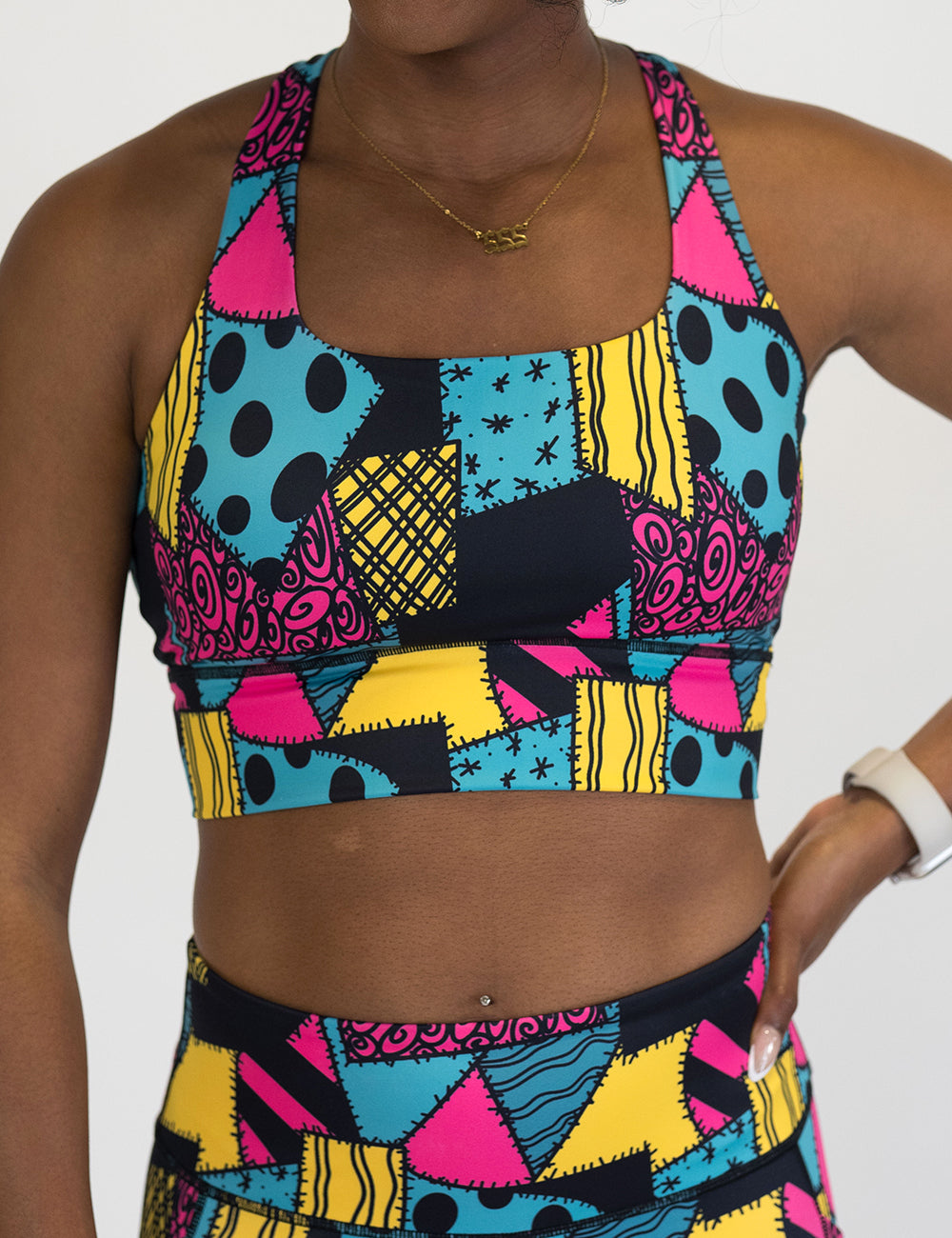 front of the yellow, teal, and pink patchwork designs bra against a white background