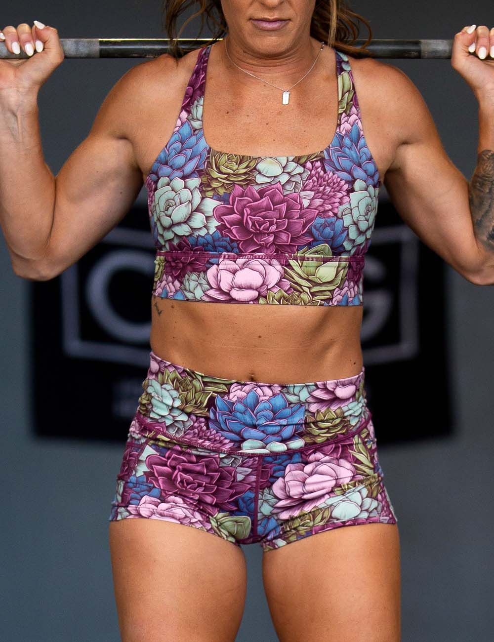 model lifting barbell wearing succulant design shorts and bras