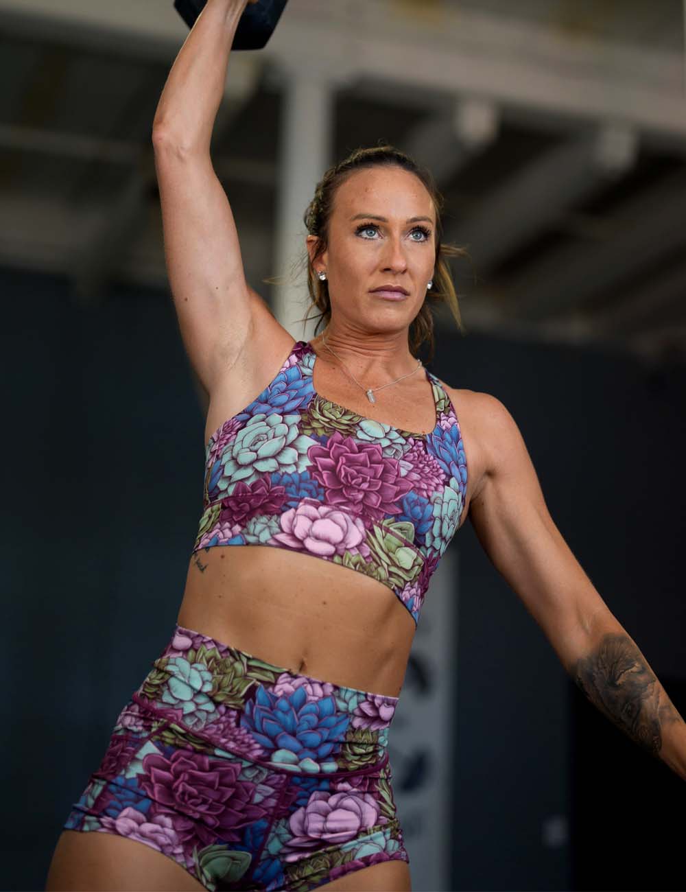 model lifting dumbbell wearing succulant patterned workout shorts and bras