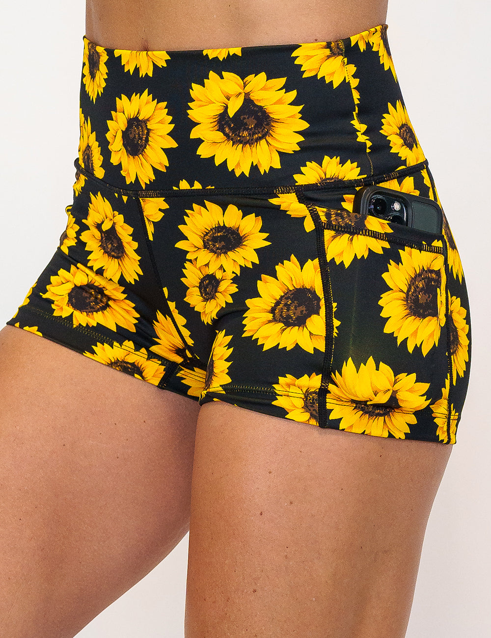 close up of the 2.5 inch yellow flower shorts holding a phone in its pocket